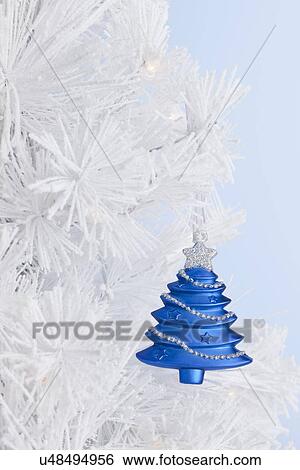 Stock Photograph - USA, Illinois, Metamora, blue Christmas bauble on white Christmas tree, close-up. Fotosearch