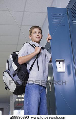 Stock Image - USA, Illinois, Metamora, Boy (10-11) standing at open locker in school corridor. Fotosearch