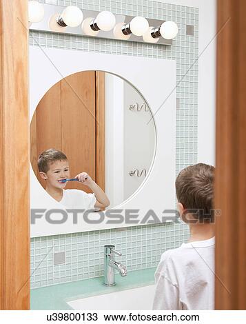 Stock Image - USA, Illinois, Metamora, Boy (6-7) brushing teeth in bathroom. Fotosearch