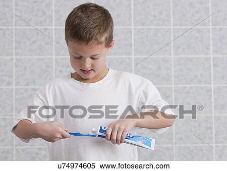 Stock Photography - USA, Illinois, Metamora, Boy (6-7) applying toothpaste to toothbrush. Fotosearch