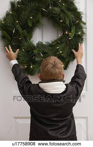 USA, Illinois, Metamora, Boy (7-8) hanging christmas wreath on door View Large Photo Image Stock Photo - USA, Illinois, Metamora, Boy (7-8) hanging christmas wreath on door. Fotosearch