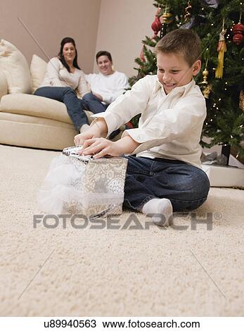 USA, Illinois, Metamora, boy (8-9) opening Christmas present, parents looking at him View Large Photo Image Stock Image - USA, Illinois, Metamora, boy (8-9) opening Christmas present, parents looking at him. Fotosearch