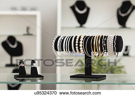 Stock Image - USA, Illinois, Metamora, bracelets and rings on display in jewelry store. Fotosearch