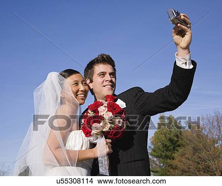 Picture - USA, Illinois, Metamora, Bride and groom photographing themselves. Fotosearch