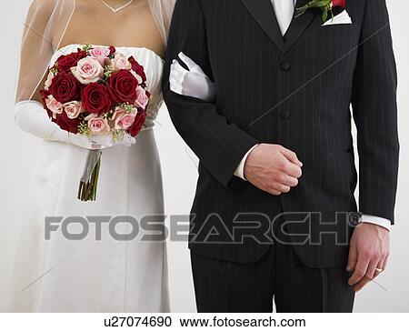 Stock Image - USA, Illinois, Metamora, Bride and groom standing arm in arm. Fotosearch