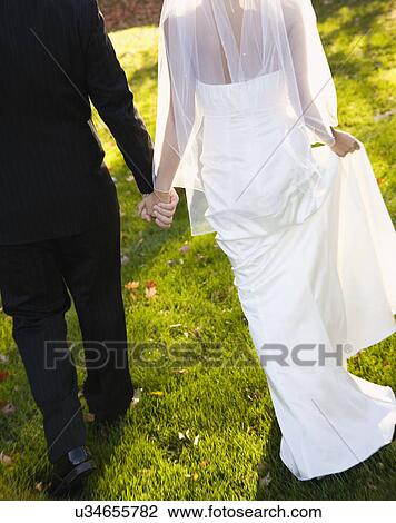USA, Illinois, Metamora, Bride and groom holding hands View Large Photo Image Stock Image - USA, Illinois, Metamora, Bride and groom holding hands. Fotosearch