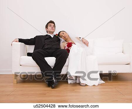 USA, Illinois, Metamora, Bride and groom relaxing on sofa View Large Photo Image Stock Photo - USA, Illinois, Metamora, Bride and groom relaxing on sofa. Fotosearch