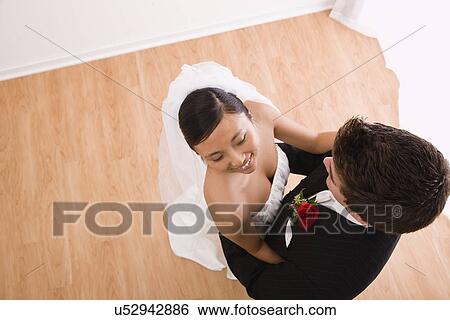 Stock Photograph - USA, Illinois, Metamora, Bride and groom embracing indoors. Fotosearch