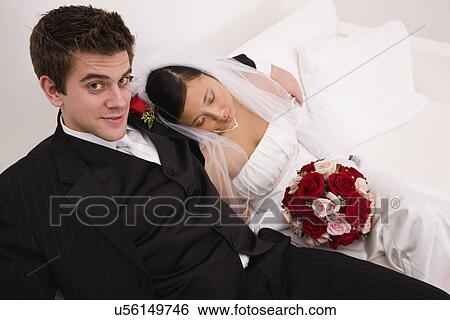 Stock Photograph - USA, Illinois, Metamora, Bride and groom relaxing on sofa. Fotosearch