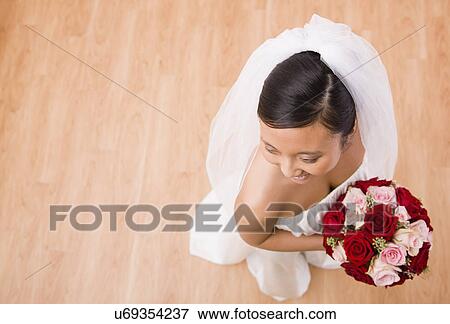 USA, Illinois, Metamora, Bride holding bouquet indoors View Large Photo Image Stock Photo - USA, Illinois, Metamora, Bride holding bouquet indoors. Fotosearch