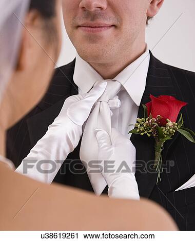 Stock Image - USA, Illinois, Metamora, Bride adjusting grooms tie. Fotosearch