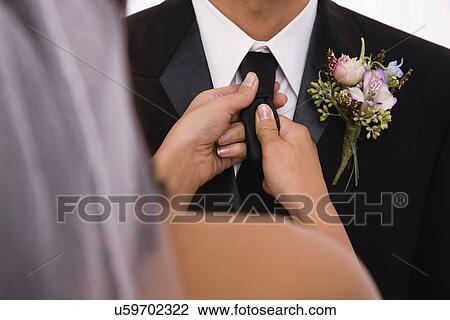 Stock Image - USA, Illinois, Metamora, bride adjusting groom's tie. Fotosearch