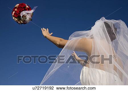 Stock Image - USA, Illinois, Metamora, Bride throwing bouquet. Fotosearch
