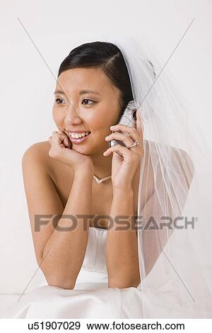 Stock Photo - USA, Illinois, Metamora, Bride using mobile phone, Smiling. Fotosearch