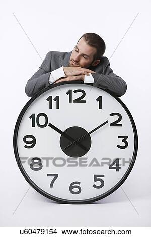 USA, Illinois, Metamora, Business man resting on large clock View Large Photo Image Picture - USA, Illinois, Metamora, Business man resting on large clock. Fotosearch