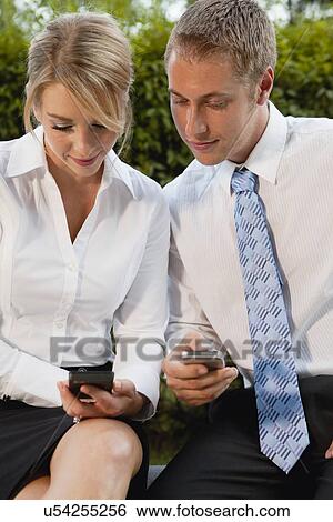 Stock Photograph - USA, Illinois, Metamora, business man and woman using cell phones. Fotosearch