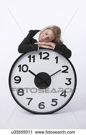 Stock Image - USA, Illinois, Metamora, Business woman resting on large clock. Fotosearch