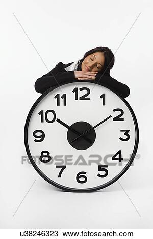 Stock Image - USA, Illinois, Metamora, Business woman resting on large clock. Fotosearch