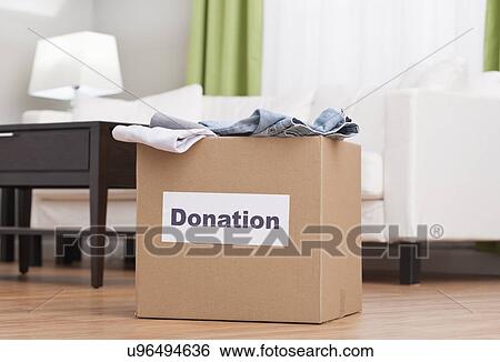 Stock Photograph - USA, Illinois, Metamora, Cardboard box with clothes in living room. Fotosearch