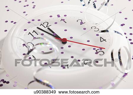 Stock Photo - USA, Illinois, Metamora, Clock with confetti and streamers showing midnight. Fotosearch