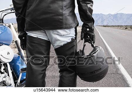 Picture - USA, Illinois, Metamora, Close up of motorcycle driver standing on road. Fotosearch