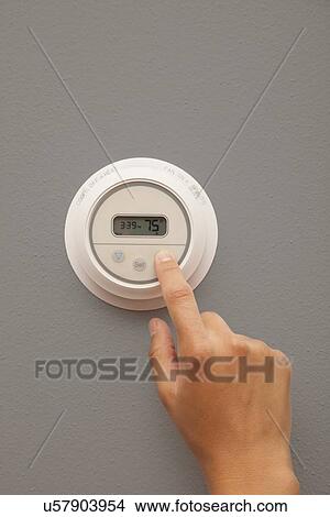 Picture - USA, Illinois, Metamora, close-up of woman adjusting thermostat. Fotosearch