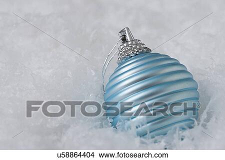 Picture - USA, Illinois, Metamora, Close up of blue Christmas ornament in snowflakes. Fotosearch