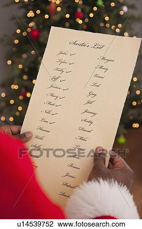 Stock Image - USA, Illinois, Metamora, Close up of hands of Santa Claus holding Santa's list. Fotosearch