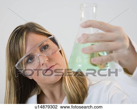 Stock Image - USA, Illinois, Metamora, close up of woman with protective glasses holding laboratory glassware. Fotosearch