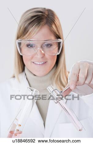 Stock Image - USA, Illinois, Metamora, close up of woman with protective glasses holding laboratory glassware. Fotosearch