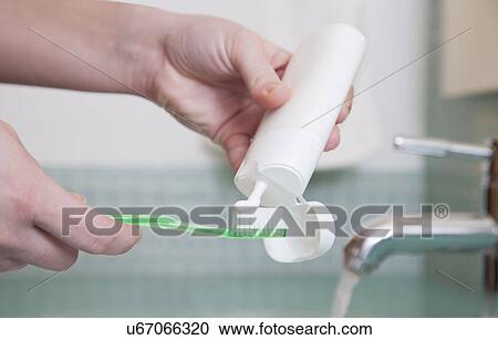 Stock Image - USA, Illinois, Metamora, close up of hands holding toothbrush and toothpaste. Fotosearch