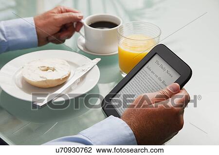 USA, Illinois, Metamora, Close-up of businessman reading e-book at breakfast table View Large Photo Image Stock Image - USA, Illinois, Metamora, Close-up of businessman reading e-book at breakfast table. Fotosearch