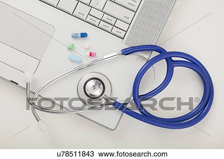 Stock Image - USA, Illinois, Metamora, Close up of medicines and stethoscope on laptop. Fotosearch
