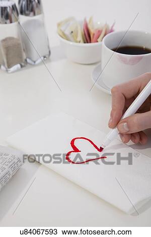 Stock Image - USA, Illinois, Metamora, Close-up of woman's hand drawing heart on napkin. Fotosearch