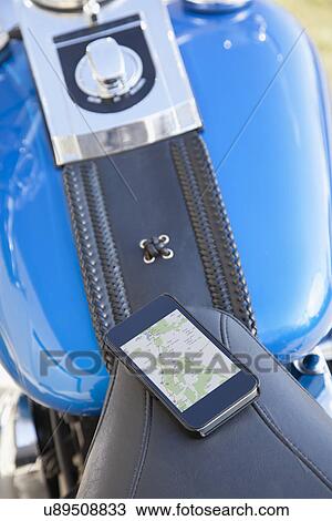 Stock Image - USA, Illinois, Metamora, Close up of smartphone with map lying on motorcycle seat. Fotosearch