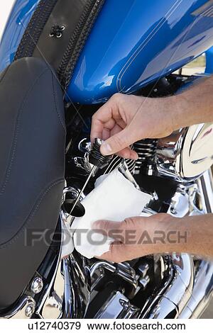 Stock Photo - USA, Illinois, Metamora, Close up of man's hand changing oil in motorcycle. Fotosearch
