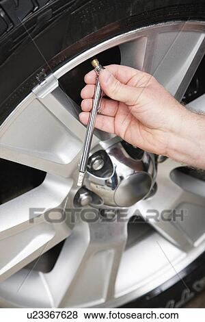 Stock Photo - USA, Illinois, Metamora, Close-up of man's hands checking tire pressure. Fotosearch