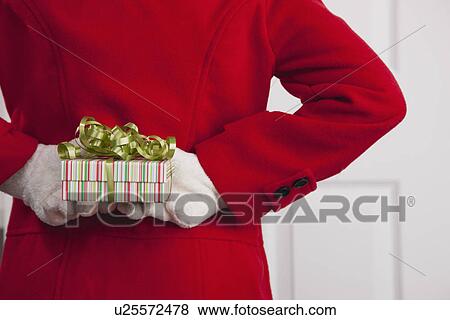 USA, Illinois, Metamora, Close up of girl (10-11) in red coat hiding Christmas gift behind her back View Large Photo Image Stock Photo - USA, Illinois, Metamora, Close up of girl (10-11) in red coat hiding Christmas gift behind her back. Fotosearch