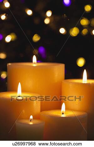 Stock Photo - USA, Illinois, Metamora, Close up of burning candles and Christmas lights in background. Fotosearch