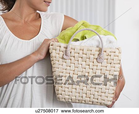 Stock Photo - USA, Illinois, Metamora, Close-up of woman carrying laundry basket, mid section. Fotosearch