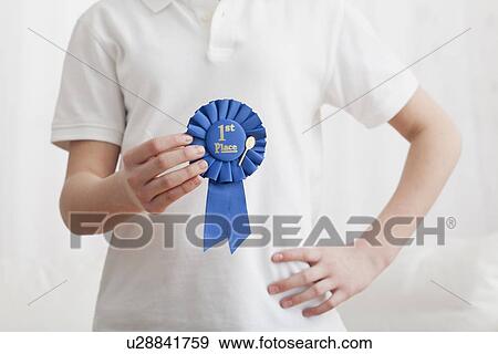 Stock Photo - USA, Illinois, Metamora, Close up of girl's (12-13) hands holding award ribbon. Fotosearch