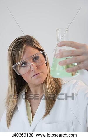 Stock Photo - USA, Illinois, Metamora, close up of woman with protective glasses holding laboratory glassware. Fotosearch