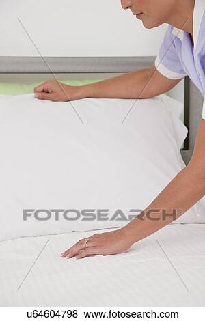 Stock Photo - USA, Illinois, Metamora, Close-up of female hotel maid making bed. Fotosearch