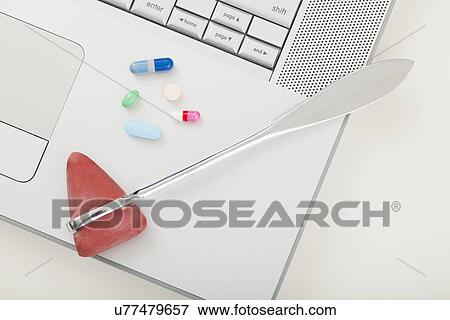 Stock Photo - USA, Illinois, Metamora, Close up of medicines and stethoscope on laptop. Fotosearch