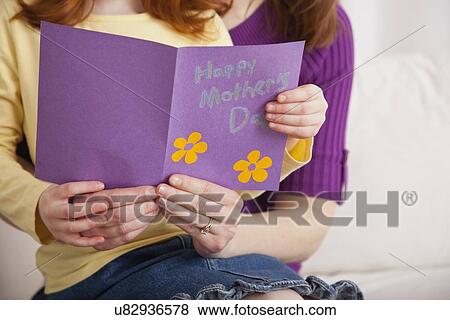 Stock Photo - USA, Illinois, Metamora, Close up of daughter (4-5) and mother holding greeting card for Mother's day. Fotosearch