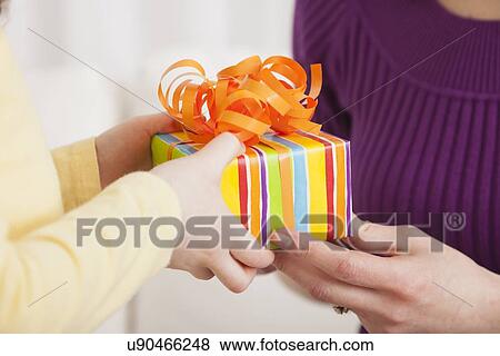 Stock Photo - USA, Illinois, Metamora, Close up of daughter's hands (4-5) giving present to her mother. Fotosearch