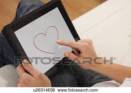 Stock Photograph - USA, Illinois, Metamora, Close-up of woman drawing heart on digital tablet. Fotosearch