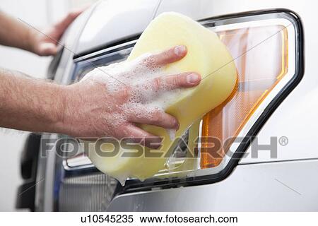 Stock Photography - USA, Illinois, Metamora, Close-up of man's hand cleaning headlight. Fotosearch