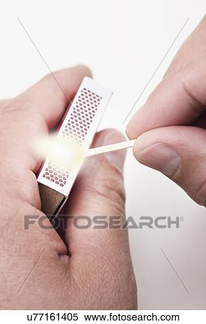 Stock Photography - USA, Illinois, Metamora, close up of man's hands holding matchbox and burning match. Fotosearch