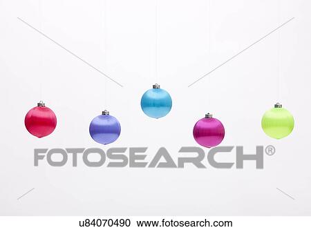 Stock Image - USA, Illinois, Metamora, Colorful Christmas ornaments hanging against white background. Fotosearch